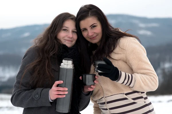 Two girlfriends with hot tea or coffee outdoors — Stock Photo, Image