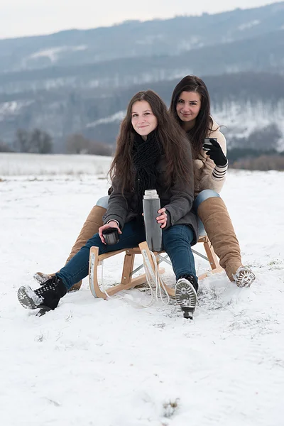Twee meisjes met hete thee of koffie buitenshuis — Stockfoto