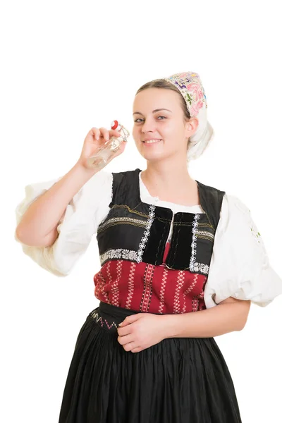 Kvinna i slovakiska folklig dräkt med en flaska alkohol Stockbild