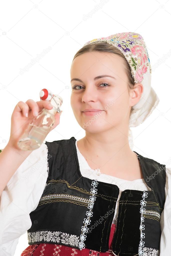 Woman in slovakian folk costume with bottle of alcohol