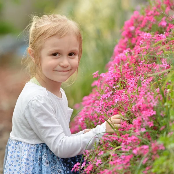 Kleines Mädchen im Garten mit Blumen — Stockfoto