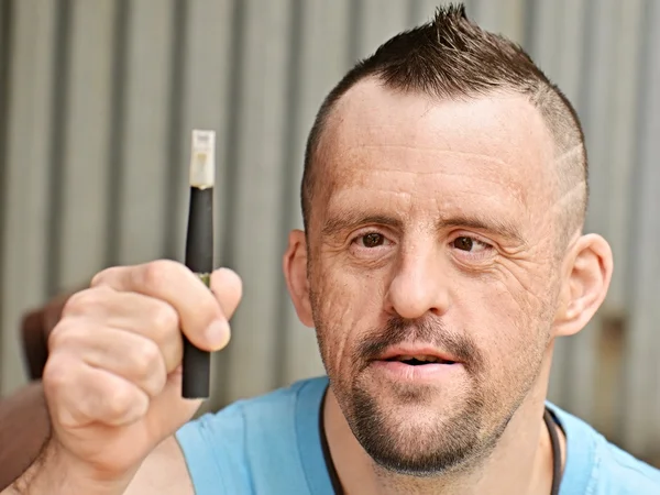 Down syndrome man with electronic cigarette — Stockfoto