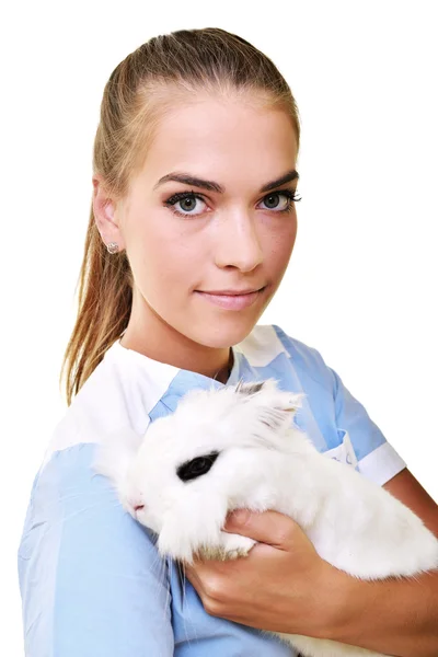 Veterinário sorrindo segurando e examinando coelho branco bonito — Fotografia de Stock