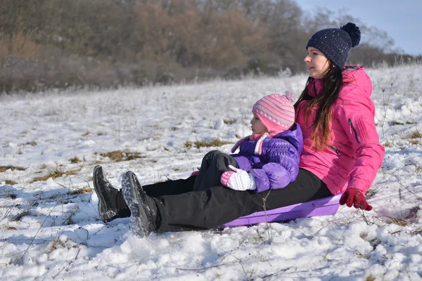 Jonge moeder en meisje genieten van sleigh ride — Stockfoto