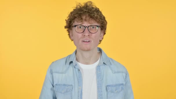 Missnöjd rödhårig ung man med förlust, gul bakgrund — Stockvideo