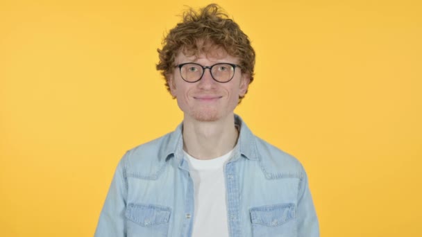 Mosolygós vörös hajú fiatalember, sárga háttér — Stock videók