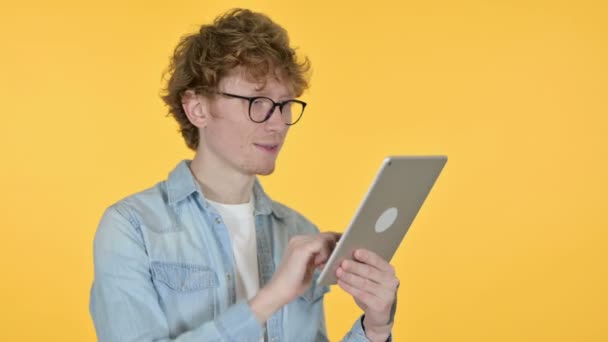 Jovem ruivo usando tablet digital, fundo amarelo — Vídeo de Stock