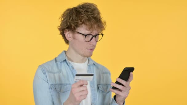 Compras en línea en Smartphone por Redhead Young Man, Fondo amarillo — Vídeos de Stock