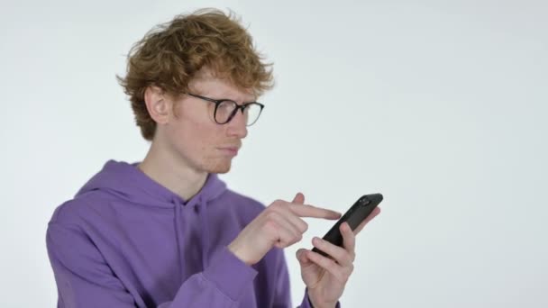 Pelirroja joven hojeando Smartphone, fondo blanco — Vídeos de Stock