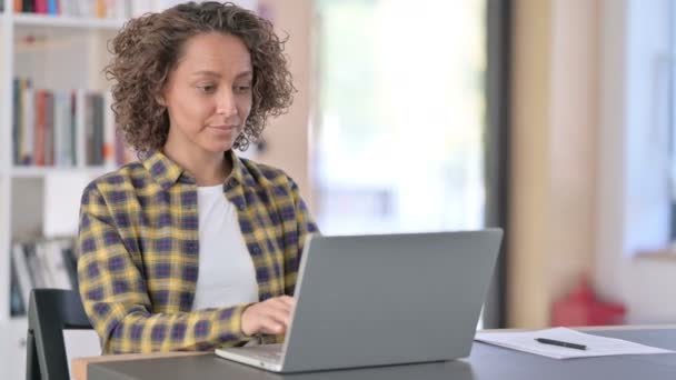 Atractiva joven mujer de raza mixta con el ordenador portátil apuntando a la cámara — Vídeo de stock