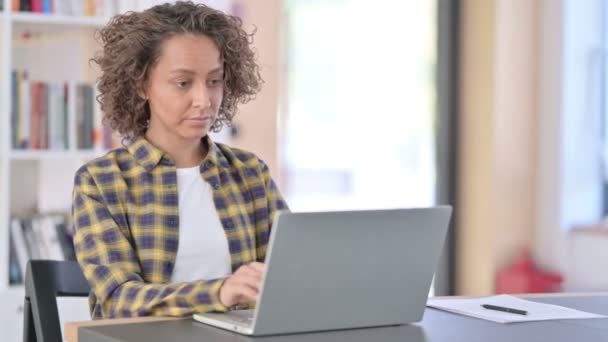 Hermosa mujer de raza mixta con portátil mirando a la cámara — Vídeos de Stock