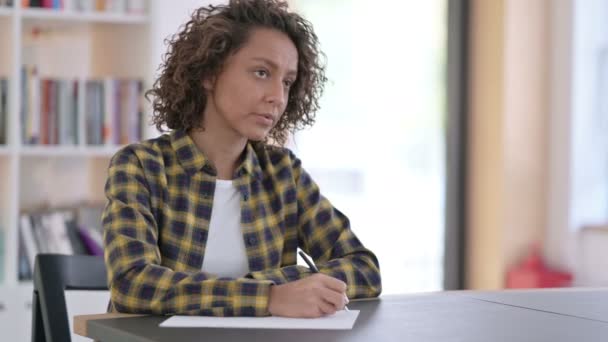 Joven mujer de raza mixta escribiendo sobre papel en el trabajo — Vídeos de Stock