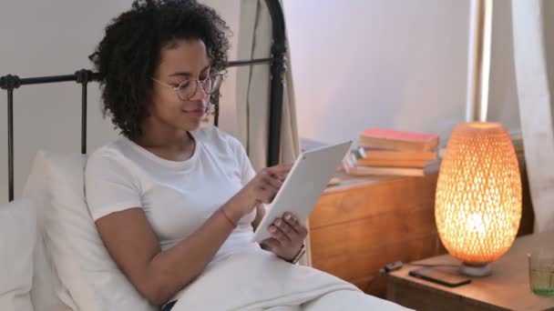 Joven mujer africana celebrando el éxito en la tableta en la cama — Vídeo de stock