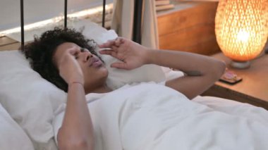 Yatakta yatan baş ağrısı olan genç Afrikalı kadın.