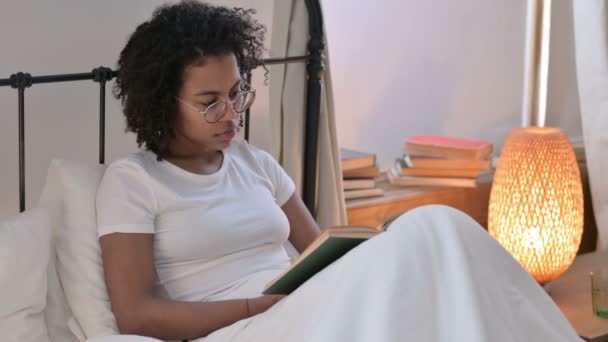 Hermosa joven africana lectura libro en la cama — Vídeo de stock