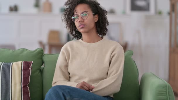 Alvorlig ung afrikansk kvinde sidder på sofaen – Stock-video