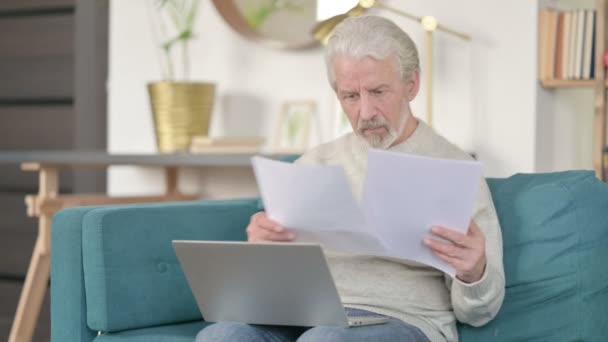 Senior oude man met documenten die werken op Laptop op Sofa — Stockvideo