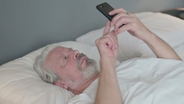 Smartphone použití Senior Old Man Ležící v posteli — Stock video