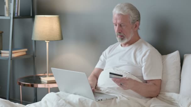 Achats en ligne sur ordinateur portable par vieil homme au lit — Video