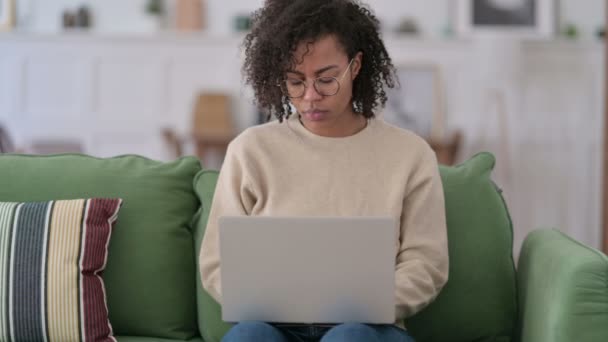 Young African Woman with Laptop Thinking on Sofa — Stock Video