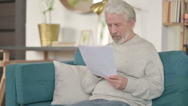 Senior Old Man med dokument som reagerar på förlust på soffan — Stockvideo