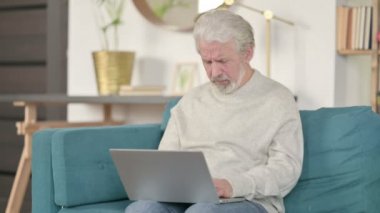 Dizüstü bilgisayarlı yaşlı adam kanepeye öksürüyor. 