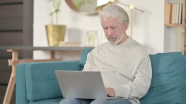 Dizüstü bilgisayarı olan yaşlı bunak koltukta başarısızlığa tepki veriyor. 