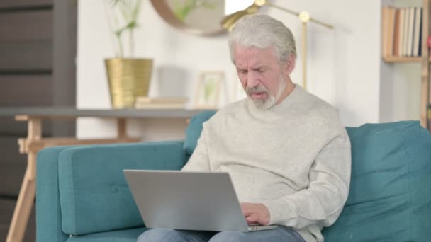 Idős öregember laptoppal fejfájással a kanapén — Stock videók