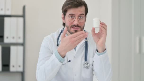 Portret van een jonge mannelijke arts die medicijnen vasthoudt en uitleg geeft — Stockvideo
