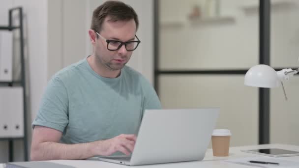 Junger Mann trinkt Kaffee beim Tippen auf Laptop — Stockvideo