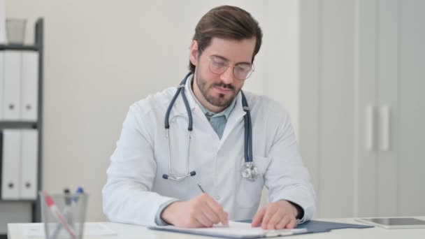 Jovem Médico Escrevendo sobre Papel no Trabalho — Vídeo de Stock