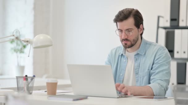 Mladý muž pracující na notebooku v kanceláři — Stock video