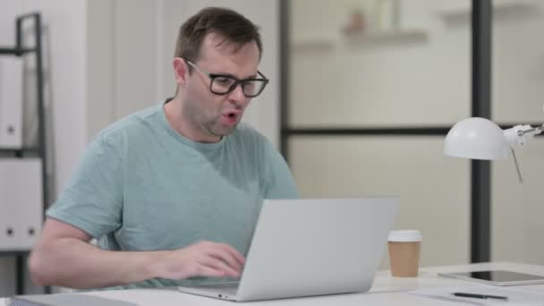 Genç adam dizüstü bilgisayarla uğraşırken sırt ağrısı çekiyor. — Stok video