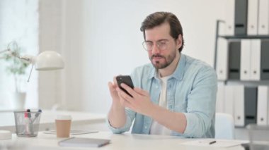 İş yerinde akıllı telefon kullanan çekici genç adam. 