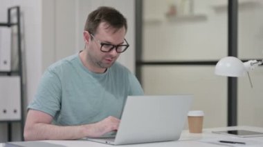 Genç adam laptopta çalışırken kestiriyor. 