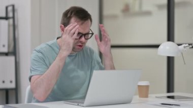 Genç adam dizüstü bilgisayarla uğraşırken baş ağrısı çekiyor 