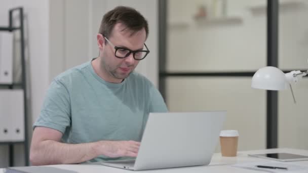 Ung man som har ont i handleden medan du arbetar på laptop — Stockvideo