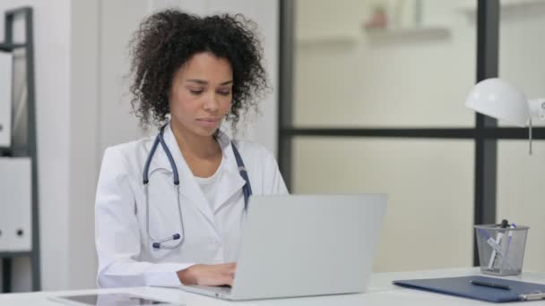 Jovem médica africana sorrindo enquanto trabalhava no laptop — Vídeo de Stock