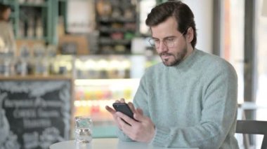 Kafe 'de akıllı telefon kullanan genç adam. 