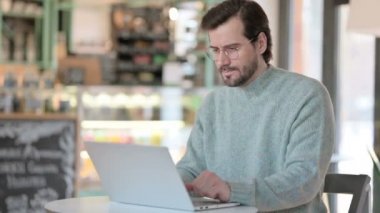 Dizüstü bilgisayarda yazarken bilek ağrısı çeken genç adam. 