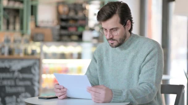 Młody człowiek czytanie dokumentów w Cafe — Wideo stockowe