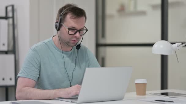 Посміхнений молодий чоловік носить навушники, телефонний центр — стокове відео