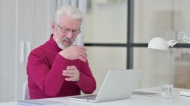 Dizüstü bilgisayar üzerinde çalışırken bilek ağrısı çeken yaratıcı yaşlı adam. 