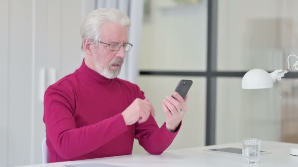 Homem velho criativo reagindo à perda no smartphone — Vídeo de Stock