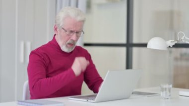 Yaratıcı yaşlı adam dizüstü bilgisayarla çalışırken öksürüyor. 