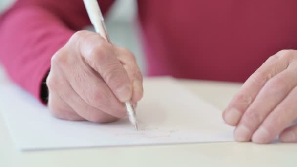 Handen van de oude man die op papier schrijft — Stockvideo
