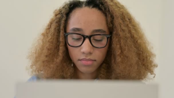 Retrato de mujer africana mirando la cámara mientras usa el ordenador portátil — Vídeos de Stock