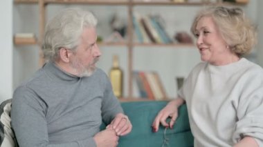 Çekici yaşlı çift koltukta otururken sohbet ediyorlar.