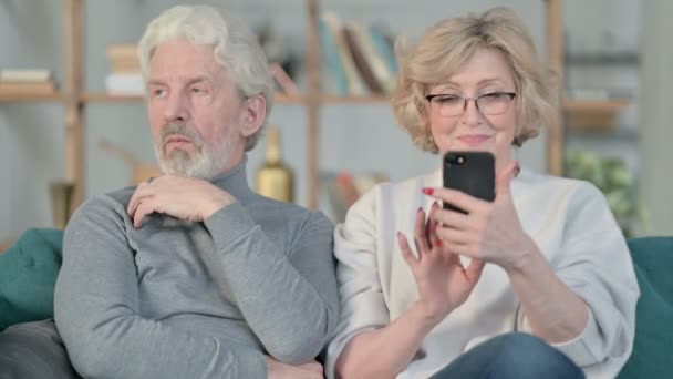 Oude vrouw druk met Smartphone, terwijl de oude man zit boos — Stockvideo