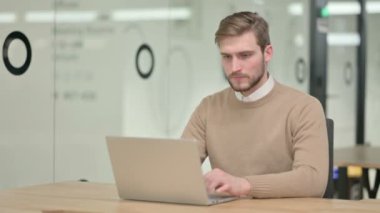 Dizüstü bilgisayarlı yaratıcı genç adam Kameraya bakıyor 